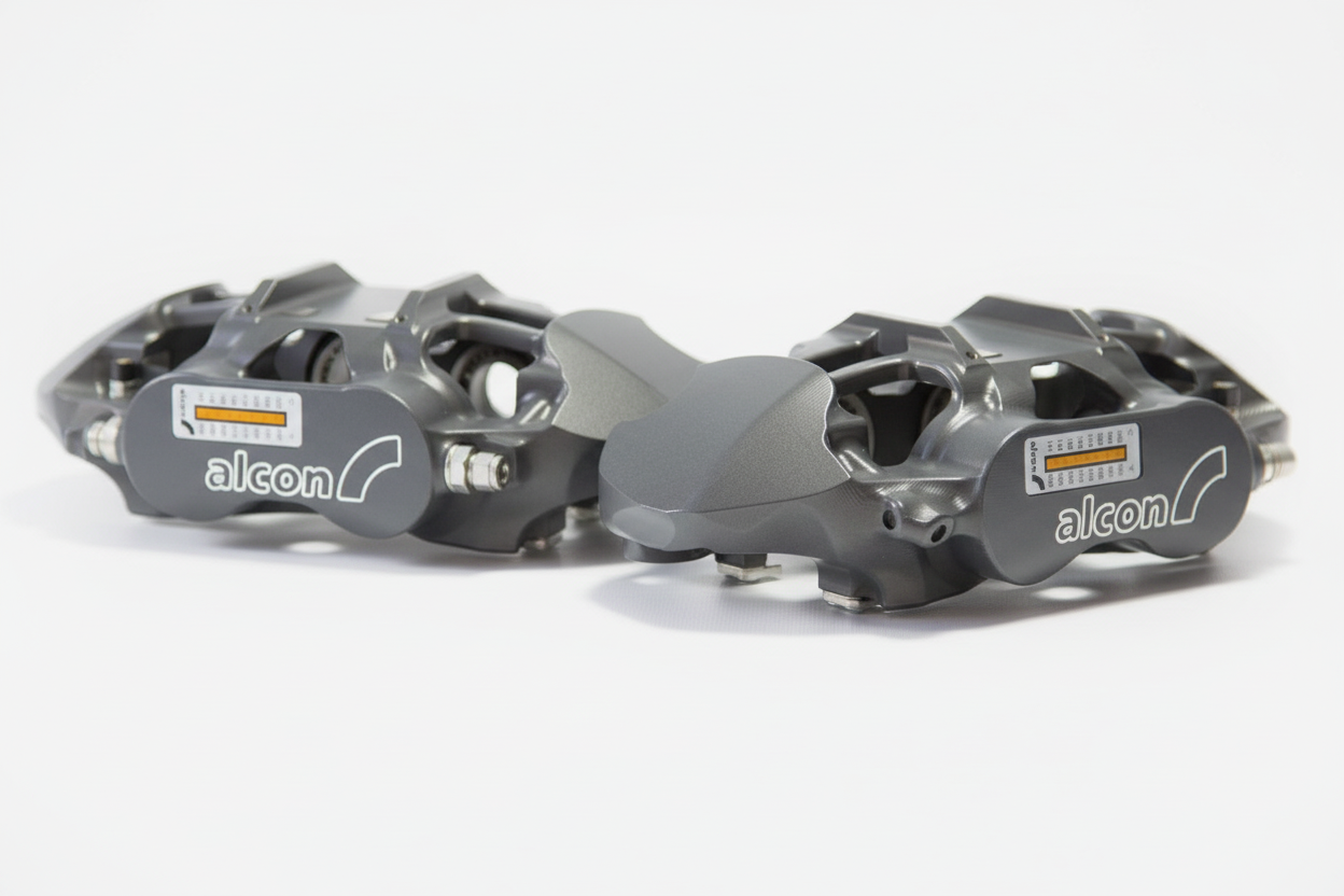 Pair of grey Alcon brake calipers with spec label